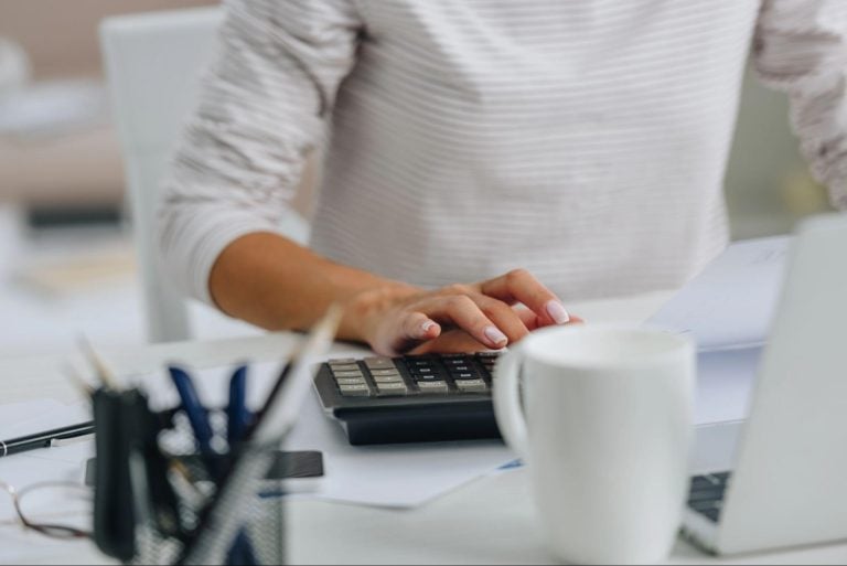 Experienced accountant working on finances using calculator at workspace.