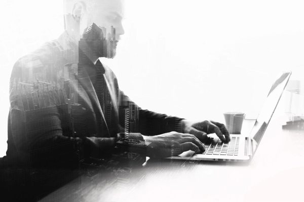 Professional accountant working on a laptop with cityscape overlay for Harlan Willow Accounting Group.